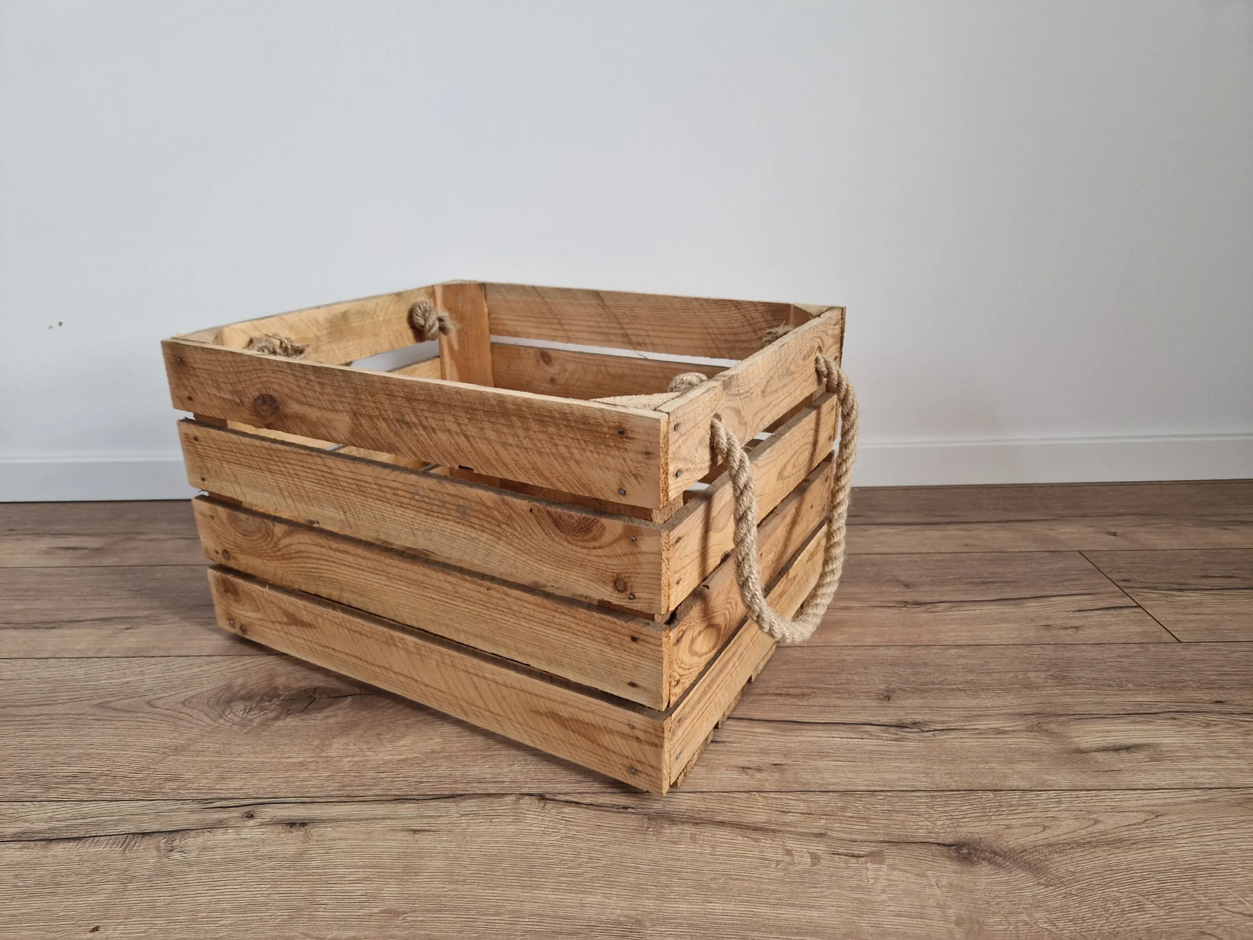 Caisse en bois flambée avec poignées en corde sur le sol