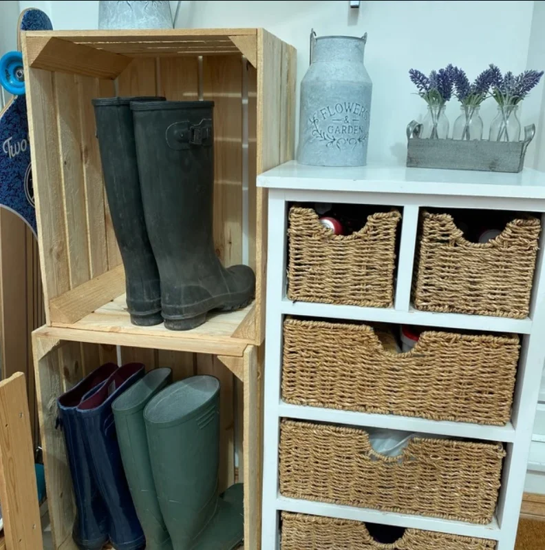 Wooden crates and wicker baskets on shelves next to wellington boots