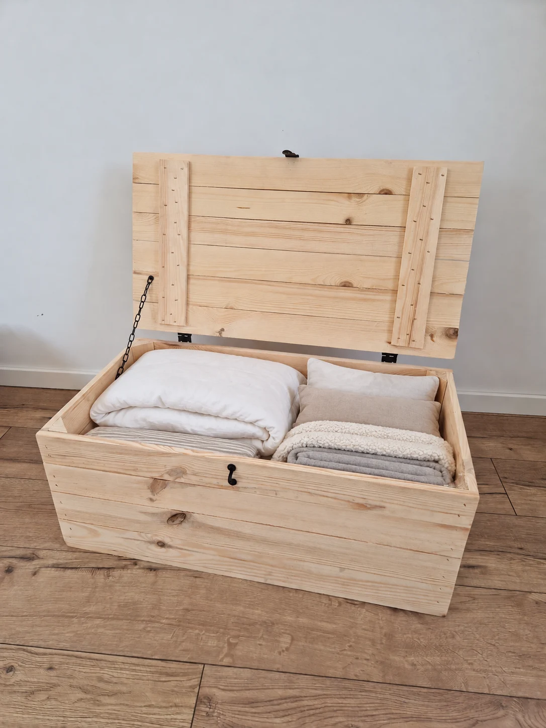 Open wooden chest for bedding with pillows and blankets